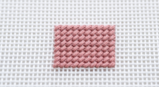 Evenly tensioned tent stitches lying flat on needlepoint canvas — correct relaxed tension