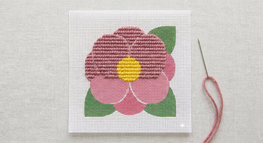 Partially stitched camellia needlepoint canvas showing flat tent stitches next to printed unstitched areas
