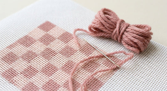 Printed checkerboard needlepoint canvas with threaded needle ready to begin