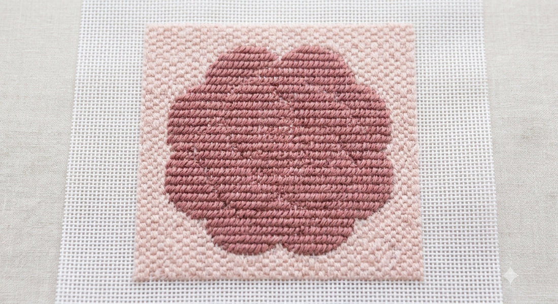 Stitched rose flower popping forward from a subtler textured needlepoint background